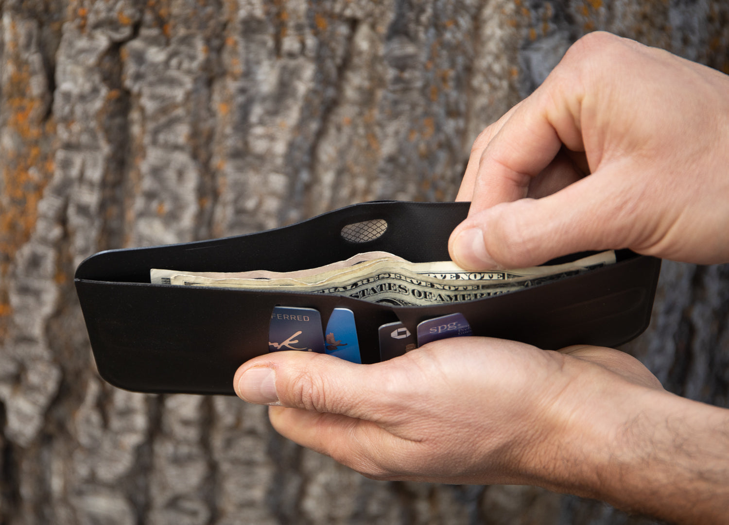 image of the incremental bifold wallet open with cash inside and a hand starting to pull cash out