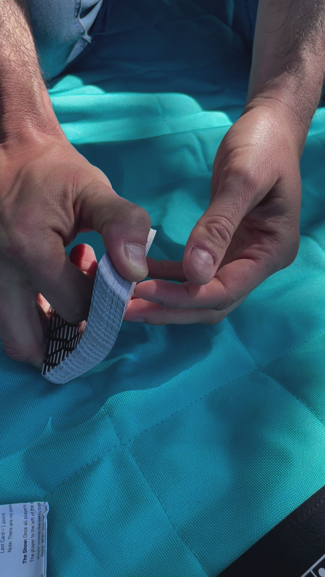 Video of the incremental playing cards being shuffled on a blue blanket outside